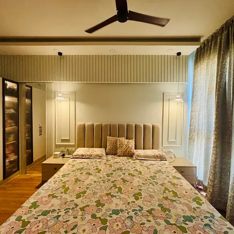 Bedroom with a channel-tufted fabric headboard flanked by pendant lights, sage-green fluted wall panelling