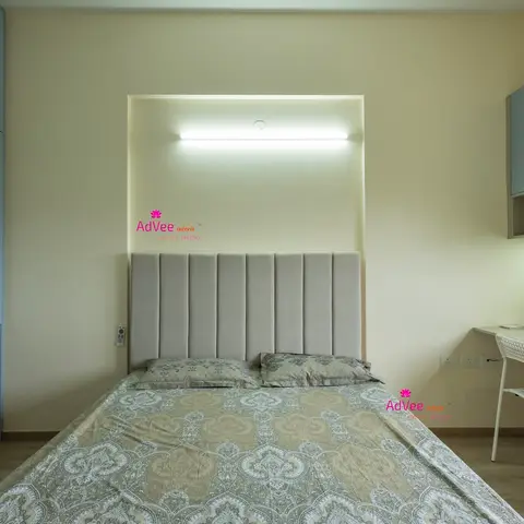 Bedroom with a channel-tufted grey headboard set into a lit wall niche, a slate-blue wardrobe on one side and a built-in study desk with overhead cabinet on