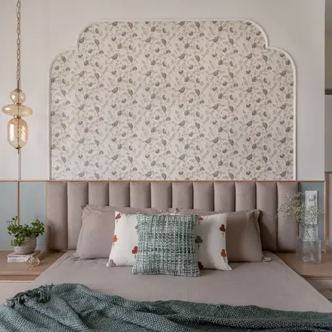 Bedroom with a channel-tufted headboard set against an arched floral-wallpaper wall, flanked by built-in wood nightstands and a sage-green door.