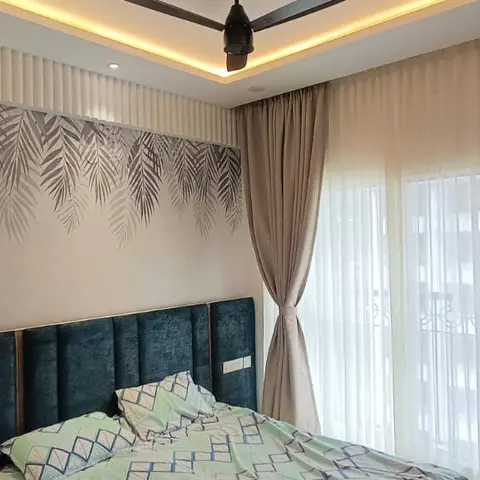 Bedroom with a channel-tufted navy headboard beneath a tropical leaf wall mural, green fluted panelling with an arched mirror
