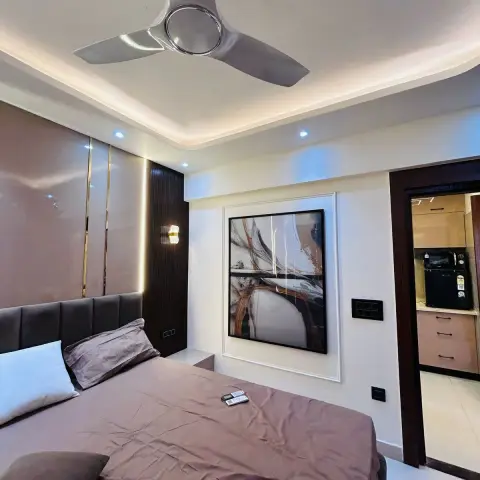 Bedroom with a channel-tufted taupe headboard against a high-gloss beige panel inlaid with brass strips