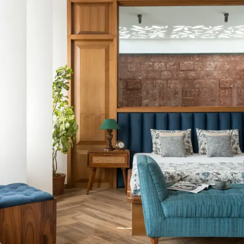 Bedroom with a channel-tufted teal upholstered headboard wall beneath a rustic textured stone-look panel, a cane-front wood nightstand