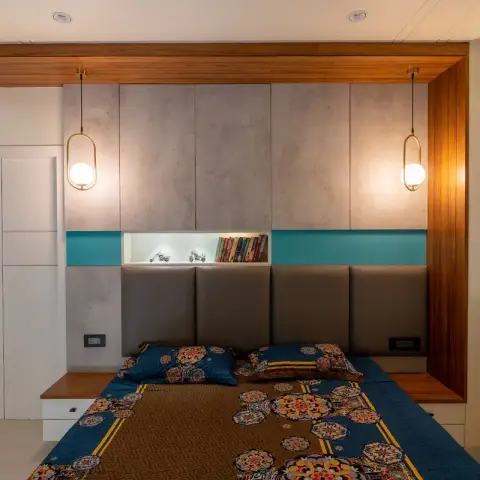 Bedroom with a concrete-textured wardrobe wall framed in wood, teal accent strips either side of an open display niche holding books and toy motorcycles