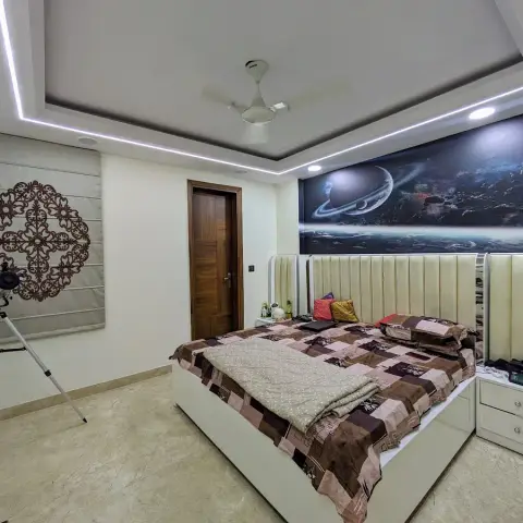 Bedroom with a cream fluted upholstered headboard running the full width of the wall under a deep-space planet mural