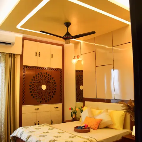 Bedroom with a cream wardrobe featuring a circular carved jaali medallion door panel, a backlit cove ceiling, mirrored wall panelling