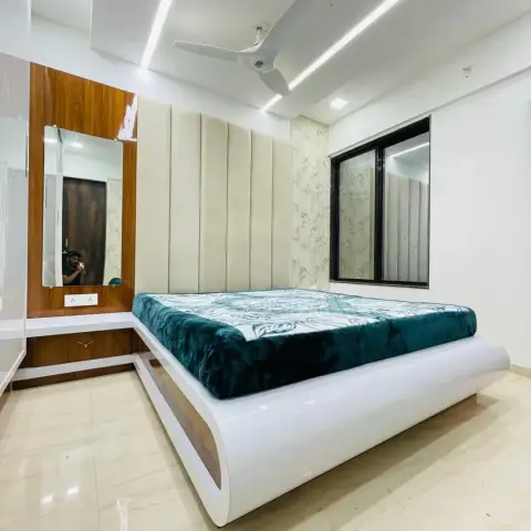 Bedroom with a curved high-gloss white platform bed under a channel-tufted cream headboard panel, a teal velvet blanket thrown over it