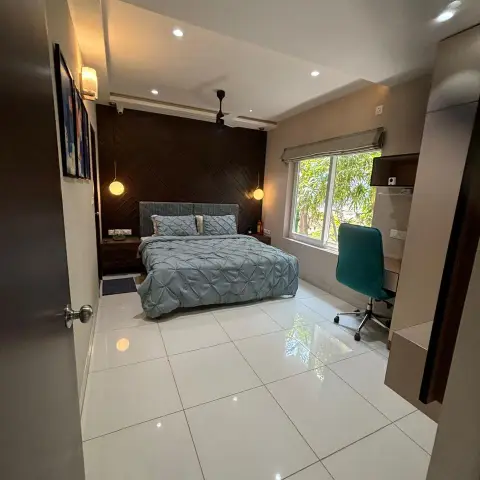 Bedroom with a dark diagonally-panelled headboard wall, twin glass globe pendants dropping either side of the bed, pintuck grey-blue bedding