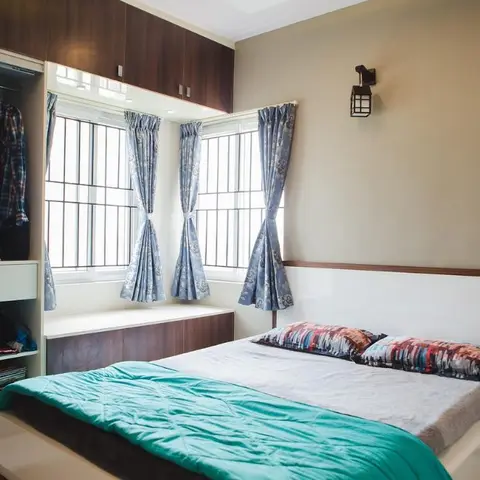Bedroom with a dark wood loft wardrobe wrapping over a built-in window seat with floral curtains, a wall-mounted lantern sconce