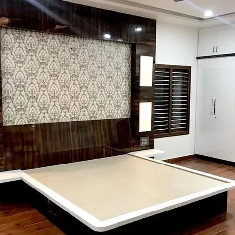 Bedroom with a dark wood-panelled headboard wall featuring a damask wallpaper inset, wall sconces, a low platform bed base and a glossy white wardrobe.