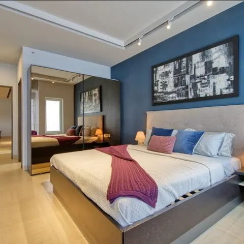 Bedroom with a deep navy textured accent wall behind a grey tufted headboard, matching bedside lamps on dark wood nightstands