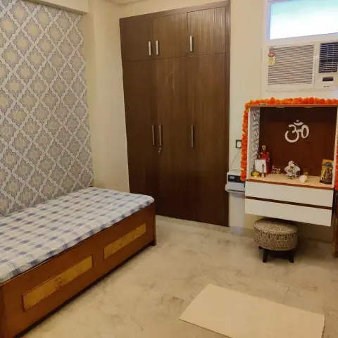 Bedroom with a diamond-patterned wallpaper accent wall behind a single bed, a dark wood wardrobe