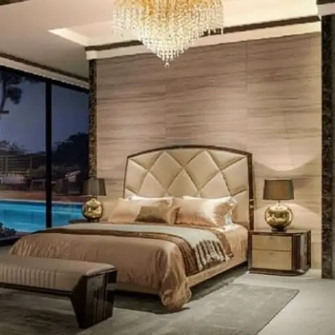 Bedroom with a diamond-tufted gold-tone leather headboard, dark wood furniture, a crystal chandelier