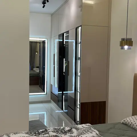 Bedroom with a fern-print quilt in the foreground, a brass pendant light by the headboard