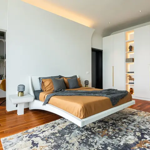 Bedroom with a floating cantilevered curved bed platform in white, rust-orange bedding
