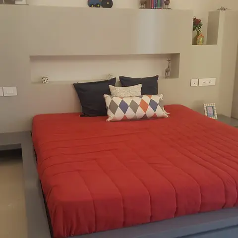 Bedroom with a floating grey platform bed and an integrated headboard wall of display niches