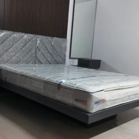 Bedroom with a floating platform bed against a dark wood-slat headboard wall and matching wall-mounted nightstands; mattress still in delivery wrap.
