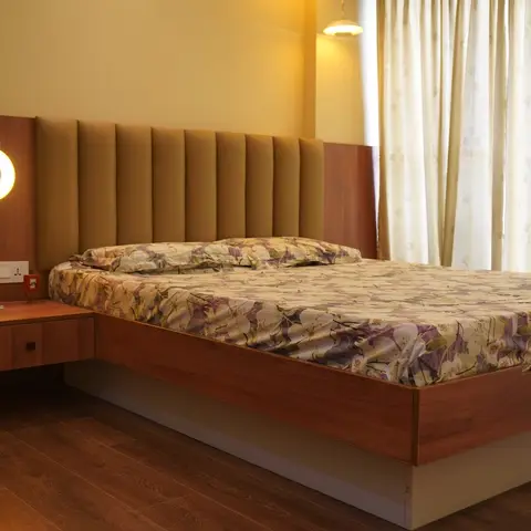 Bedroom with a floating wood platform bed with a channel-tufted headboard, a wall-mounted round reading lamp, and mustard-yellow walls.