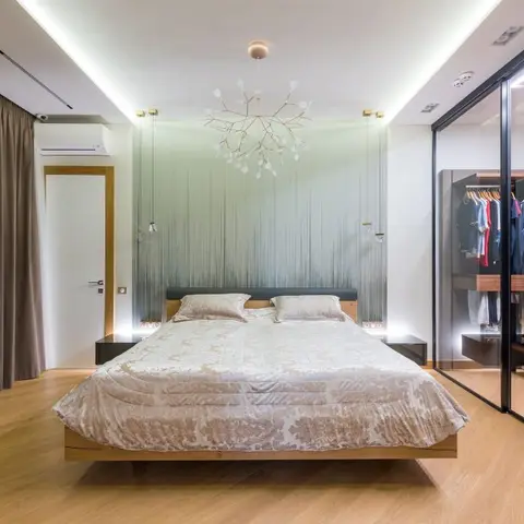 Bedroom with a floating wood platform bed beneath a sculptural branch chandelier, a sage ombre fringe accent wall
