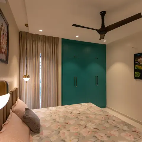 Bedroom with a floor-to-ceiling teal wardrobe on the facing wall, brass-and-opal globe pendants dropped either side of a channel-tufted beige headboard