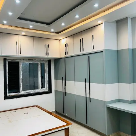 Bedroom with a floor-to-ceiling grey-and-white striped wardrobe, a built-in corner study desk, a stepped cove-lit false ceiling