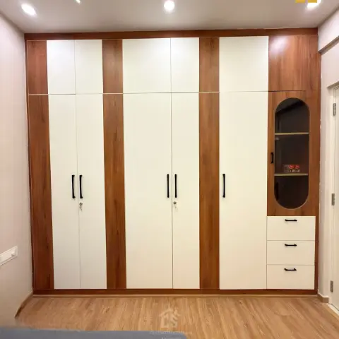 Bedroom with a floor-to-ceiling two-tone cream-and-walnut wardrobe featuring an arched glass display niche and drawer unit