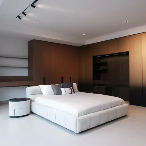 Bedroom with a floor-to-ceiling ombre bronze wardrobe wall, a floating wall-mounted desk and shelving unit, and a tufted white upholstered bed.