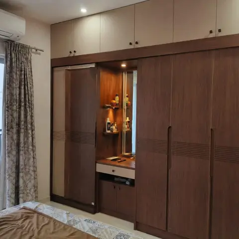 Bedroom with a floor-to-ceiling walnut-finish sliding wardrobe wall built around a lit dressing mirror nook
