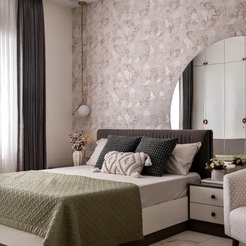Bedroom with a floral wallpaper accent wall behind an upholstered bed, beside an arched mirrored wardrobe.