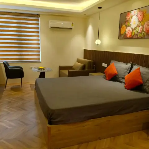 Bedroom with a fluted walnut headboard panel lit from above, a wide floral still-life canvas beside a single globe pendant on a long black flex
