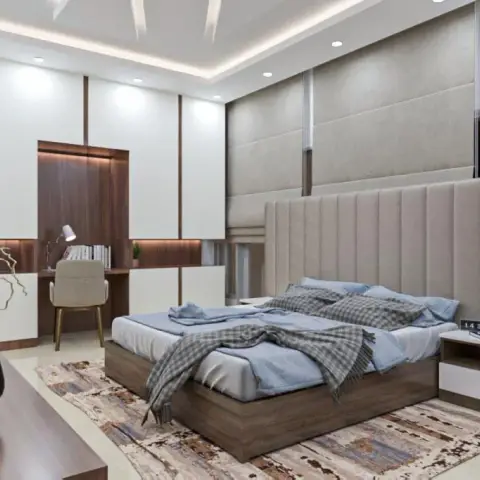 Bedroom with a full-height channel-tufted upholstered headboard wall, cove-lit ceiling, and an adjoining walnut study nook.