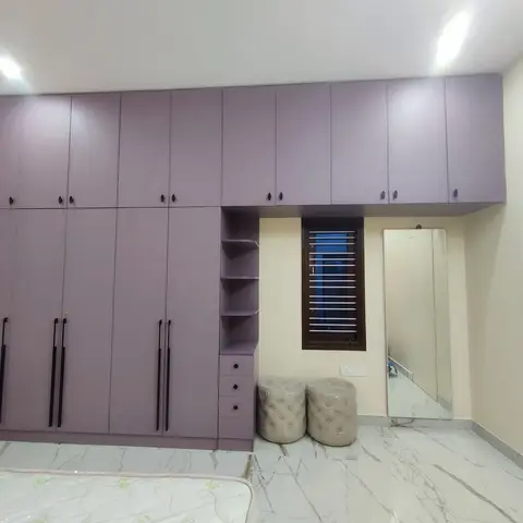 Bedroom with a full-height mauve wardrobe wall including loft storage and an open shelf column, a full-length mirror