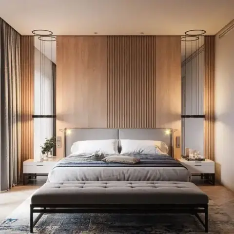 Bedroom with a full-height oak slat panel wall flanked by ring pendant lights, and a tufted bench at the foot of the bed on a herringbone wood floor.
