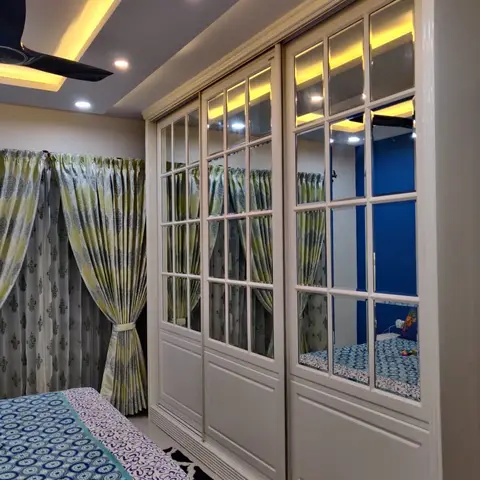 Bedroom with a full-wall mirrored sliding wardrobe, a cove-lit ceiling and coordinated green-and-blue floral curtains and bedding.