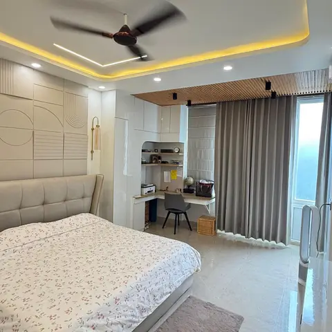 Bedroom with a geometric-embossed headboard wall, angular cove-lit false ceiling, a built-in corner study desk and slatted wood ceiling detail over a balcony