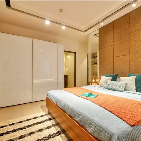 Bedroom with a glossy white sliding-door wardrobe, a jute-textured panelled headboard wall and a wood platform bed dressed in teal and rust-orange linens.