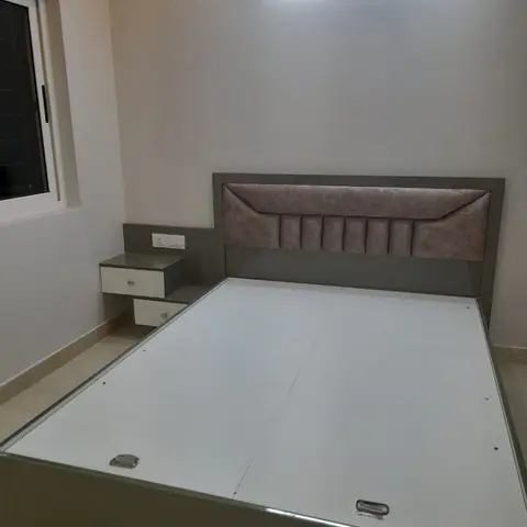 Bedroom with a grey laminate storage bed featuring a channel-tufted mauve upholstered headboard, and a matching wall-mounted bedside table with two drawers