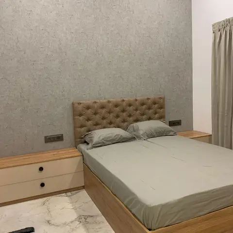 Bedroom with a grey textured-wallpaper headboard wall, a tufted tan upholstered headboard, a wood storage-bed platform
