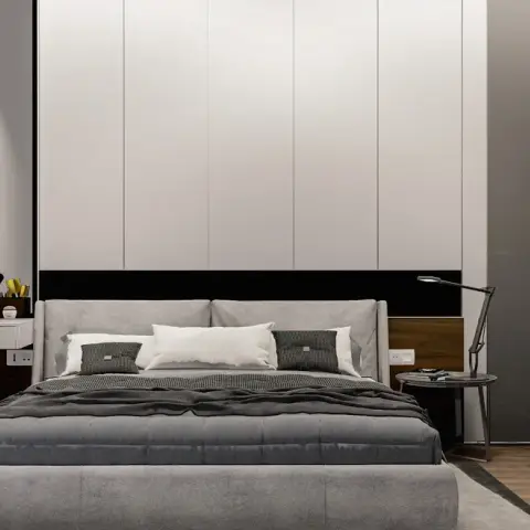 Bedroom with a grey upholstered bed and black bolster cushions, a floating makeup vanity with a stool
