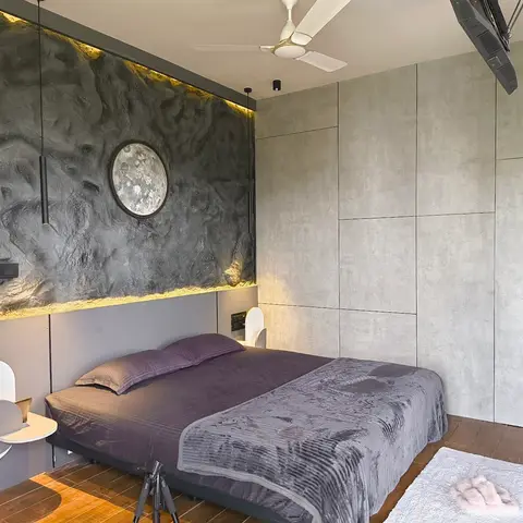 Bedroom with a heavily textured dark stucco accent wall behind the headboard, a circular moon wall-art piece, and a fluted concrete-look wardrobe wall.