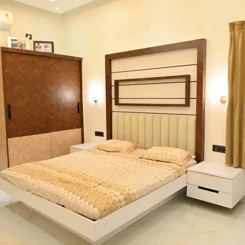 Bedroom with a herringbone-pattern wood sliding wardrobe, a wood-framed channel-tufted headboard, and floor-length gold curtains on both windows.