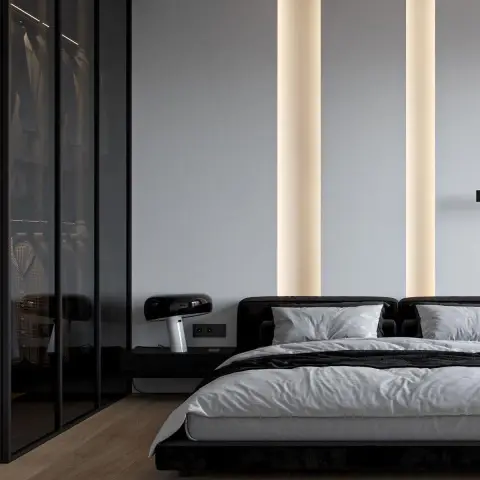 Bedroom with a low black upholstered bed, a smoked-glass walk-in wardrobe, and twin vertical LED light strips washing the wall behind the headboard.