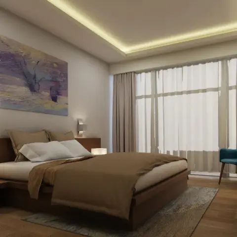 Bedroom with a low wood platform bed and wall art above the headboard, a teal accent chair by the window, and a dressing table with mirror in the corner.