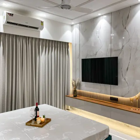 Bedroom with a marble-slab TV feature wall, brass-inlay trim, and a wine-and-candle tray staged at the foot of the bed.