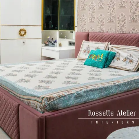 Bedroom with a mauve diamond-quilted upholstered bed against a floral-patterned wallpaper panel