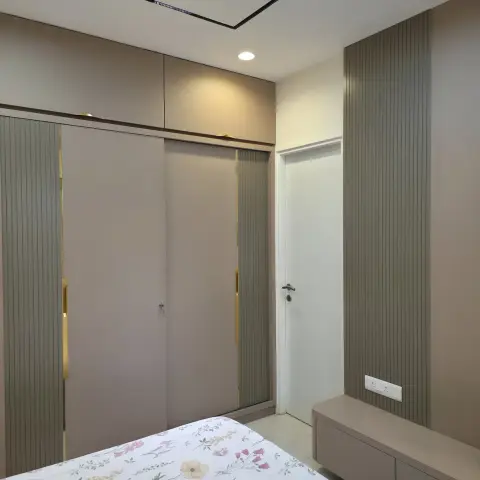 Bedroom with a mauve sliding-door wardrobe trimmed in brass, a fluted grey-panelled accent wall and a floating bedside bench.
