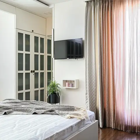 Bedroom with a mirrored-and-glass-panelled wardrobe, floor-to-ceiling ombre curtains in blush and taupe, and a window-seat daybed with block-print bolsters.