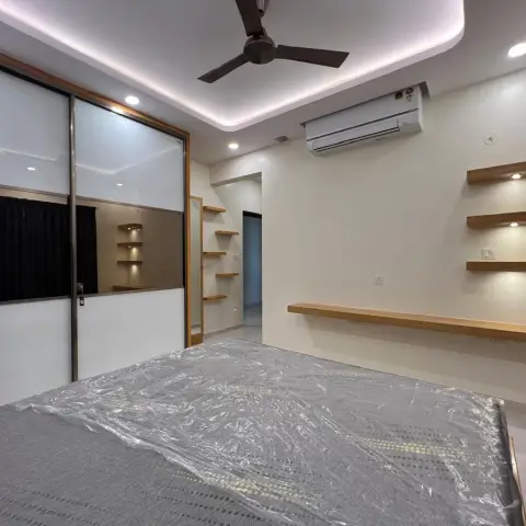 Bedroom with a mirrored sliding wardrobe, a cove-lit ceiling, floating wood display shelves, and black blackout curtains