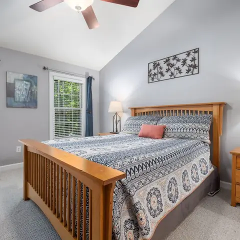 Bedroom with a mission-style wood four-poster bed, vaulted ceiling, matching bedside lamps on wood nightstands