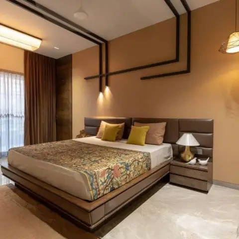 Bedroom with a mustard accent wall traced by a continuous black linear ceiling-to-wall trim, a floating dark-wood platform bed, and a printed floral bedspread.