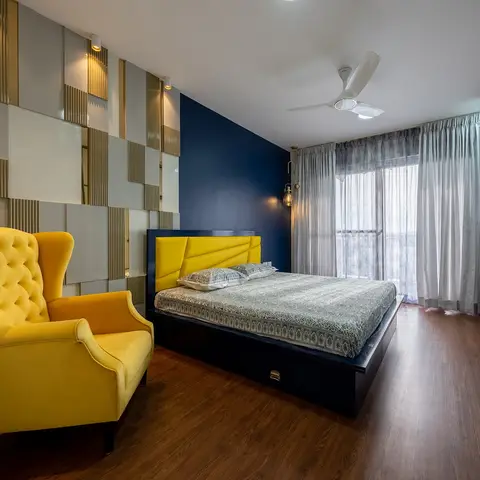 Bedroom with a mustard channel-tufted upholstered headboard and matching wingback chair against a navy accent wall